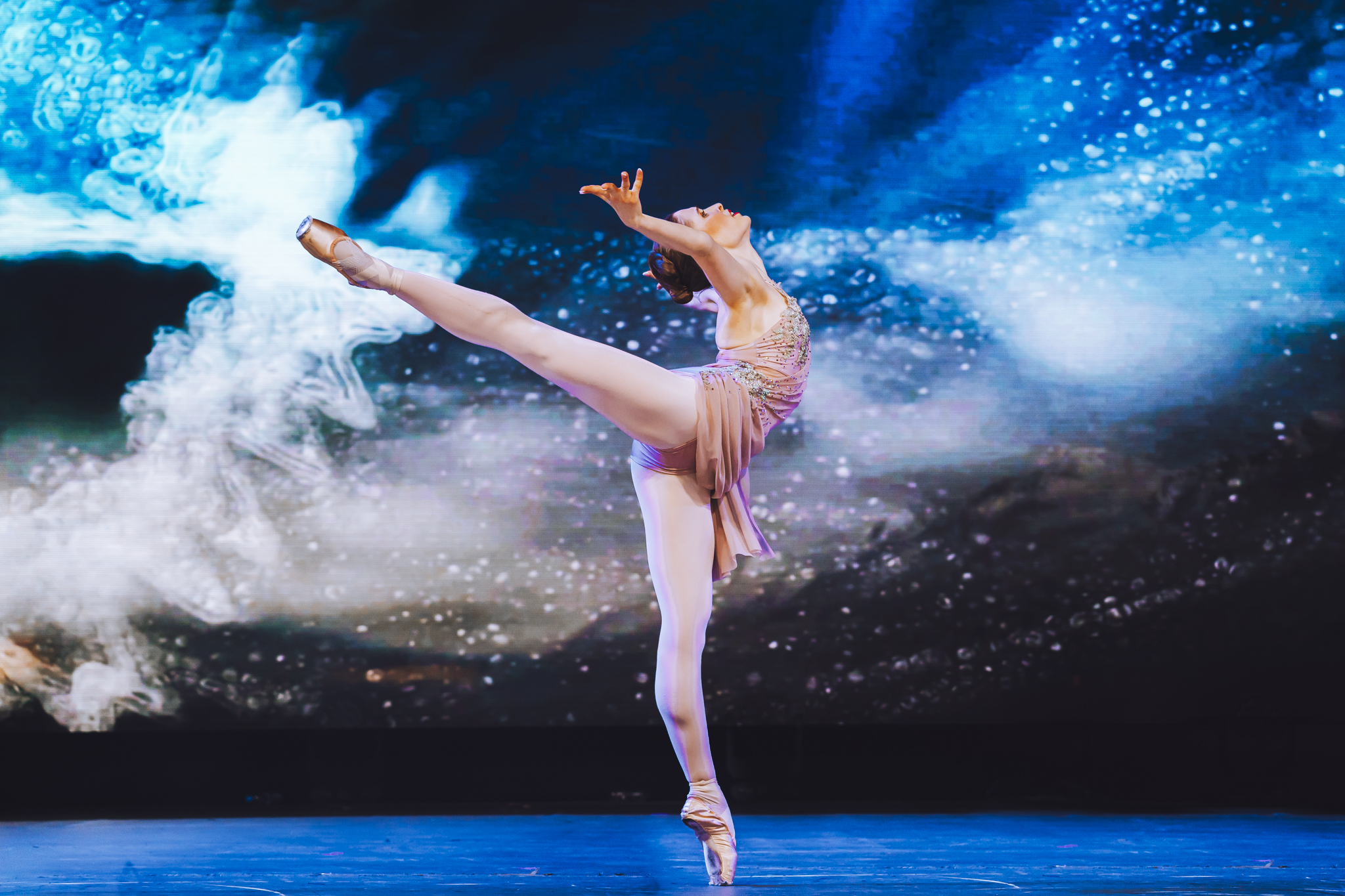 Hannah performing on pointe against blue stage lighting